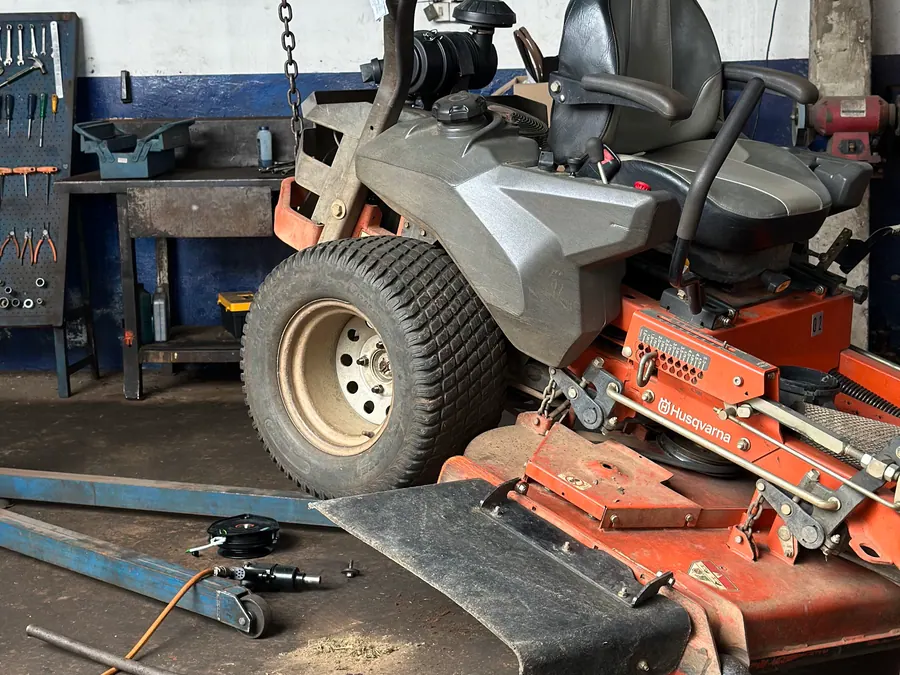 Giro zero Husqvarna sobre o elevador da oficina da Vardão, com o prato de corte removido para revisão
